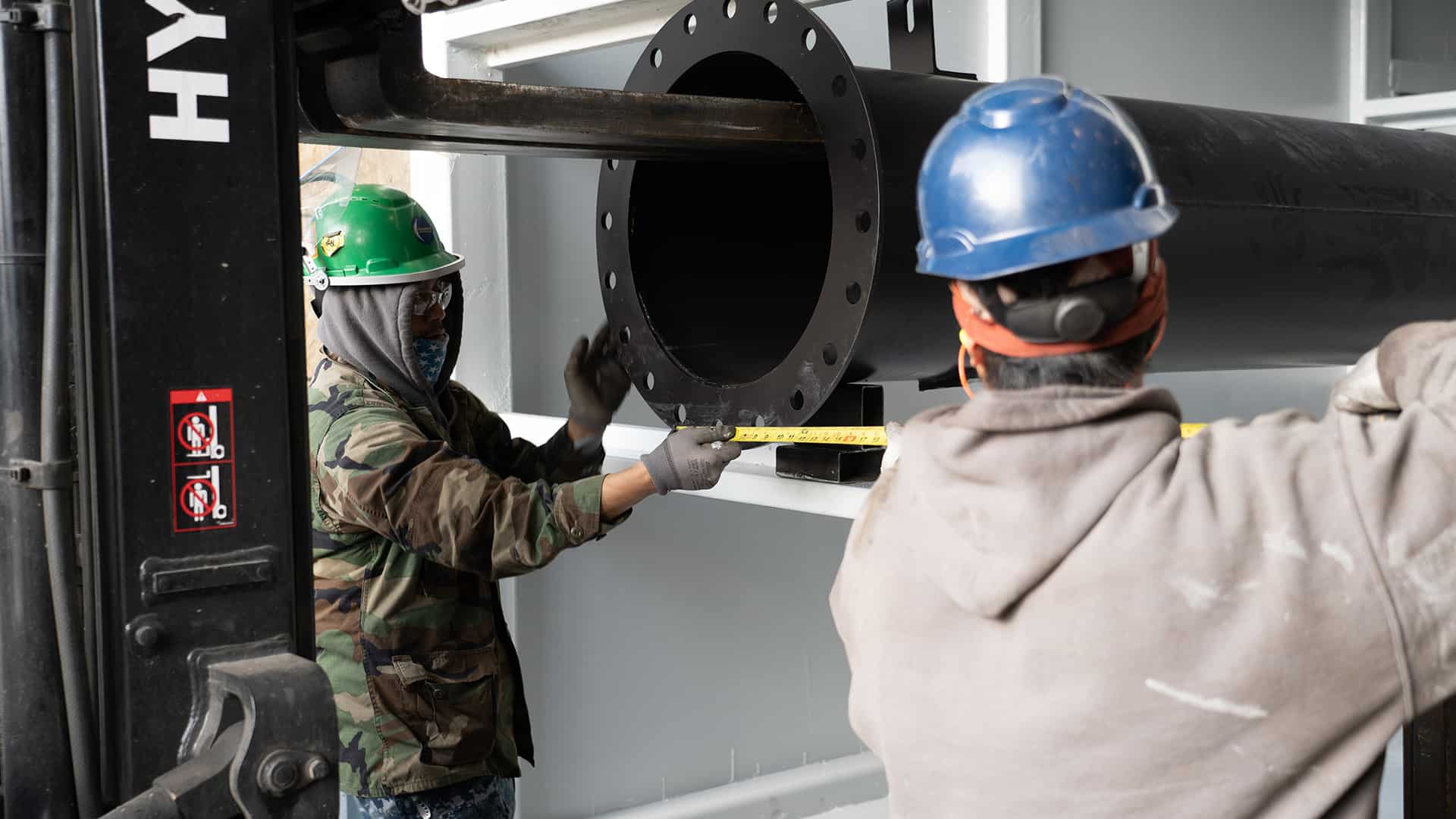 workers measuring and placing exhaust pipe in plenum Acoustical Sheetmetal Company