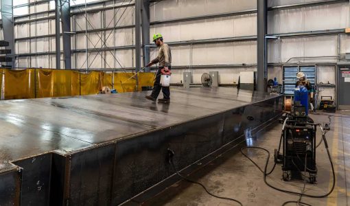 An ASC employee spraying a fuel tank on their production floor to perform a welding bubble leak test.